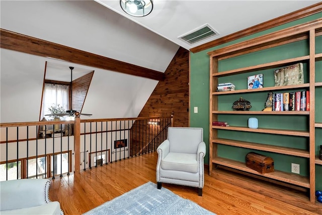 living area featuring visible vents, lofted ceiling with beams, wood finished floors, and ceiling fan