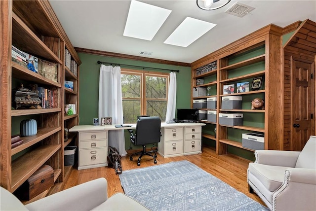 office with crown molding, visible vents, a skylight, and light wood-style floors