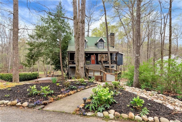 view of front of home with a porch, stairway, metal roof, and a chimney