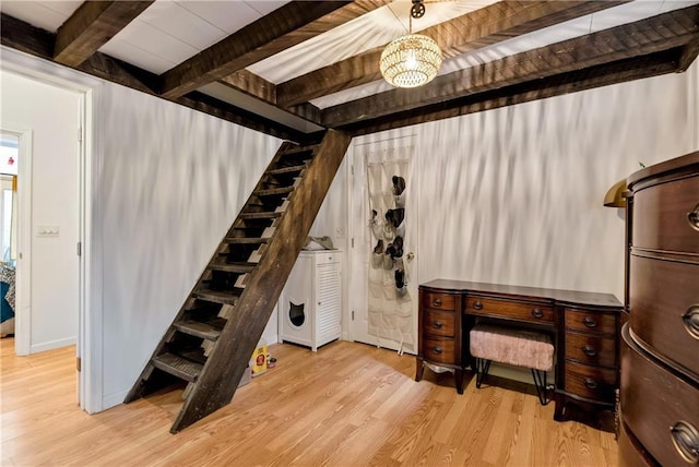 stairway featuring wood finished floors, beamed ceiling, and an inviting chandelier