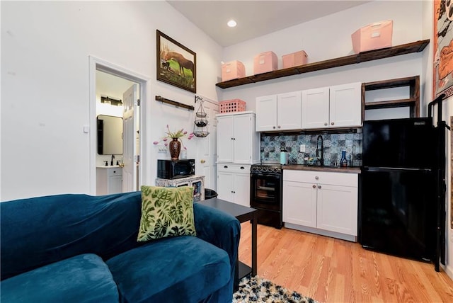 kitchen featuring light wood-style floors, white cabinetry, open shelves, black appliances, and a sink