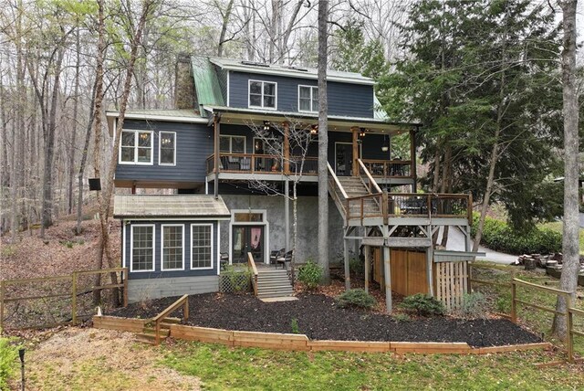 back of property featuring stairway, metal roof, stucco siding, and fence