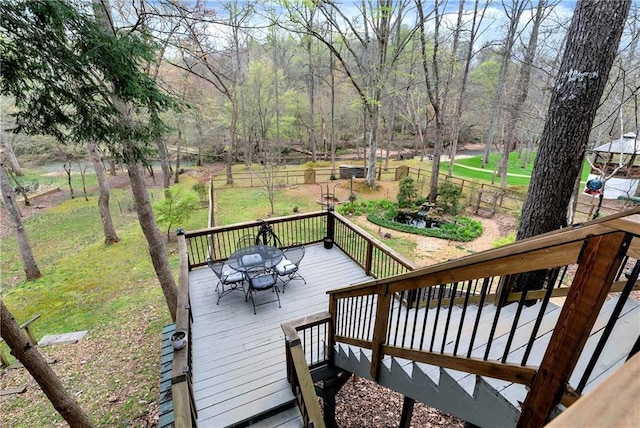 wooden deck with outdoor dining space, fence, and a lawn