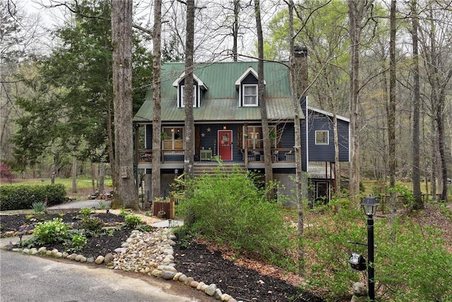 chalet / cabin with a porch, stairs, metal roof, and a chimney