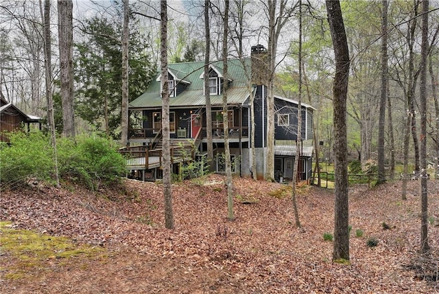 rear view of house featuring a chimney and metal roof