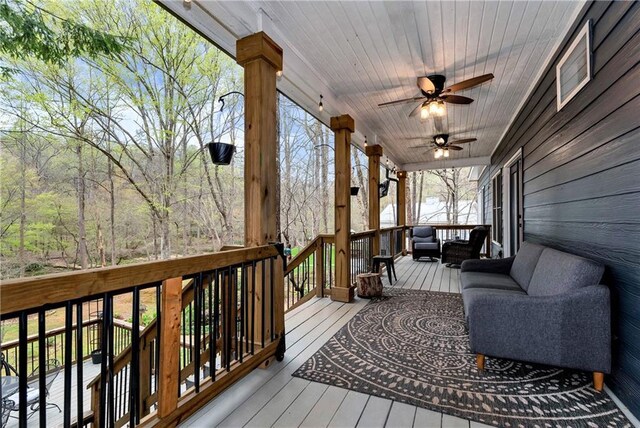 wooden deck with an outdoor living space and a ceiling fan
