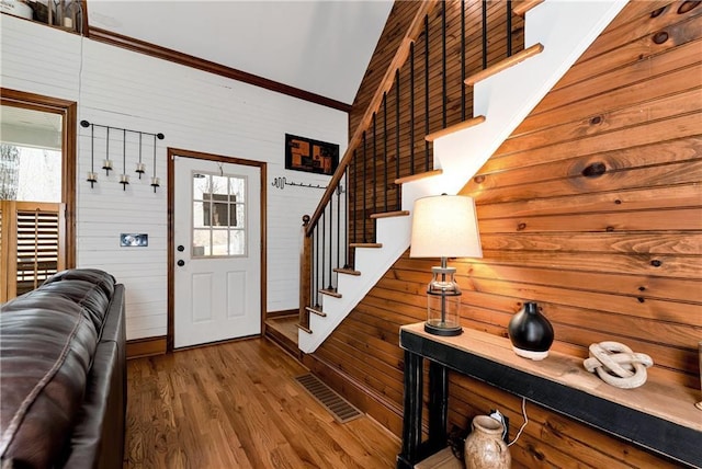 entryway featuring ornamental molding, visible vents, stairway, wood finished floors, and baseboards