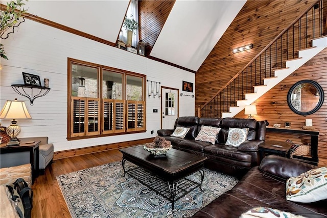 living area featuring wooden walls, high vaulted ceiling, stairway, and wood finished floors