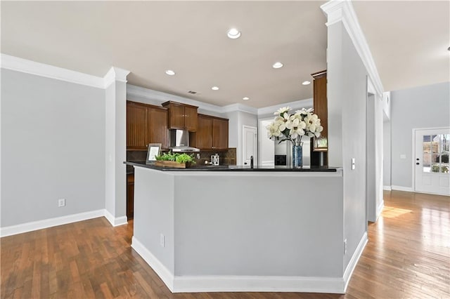 120 Daniel Creek Ln, Sugar Hill, GA 30518 - kitchen featuring wall chimney range hood, crown molding, dark countertops, dark wood-type flooring, and backsplash