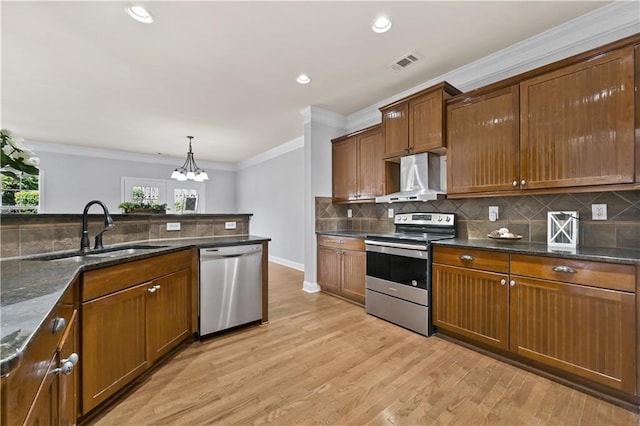 120 Daniel Creek Ln, Sugar Hill, GA 30518 - kitchen featuring stainless steel appliances, wall chimney range hood, light wood-type flooring, backsplash, and crown molding
