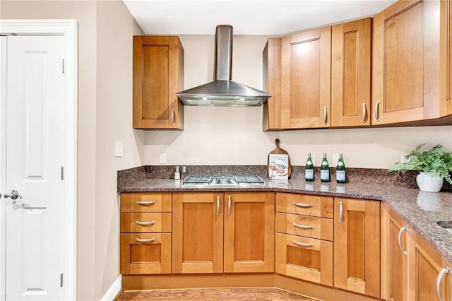 2881 Peachtree Rd NE Unit 1202, Atlanta, GA 30305 - kitchen featuring wall chimney exhaust hood, stainless steel gas stovetop, brown cabinets, dark stone countertops, and light wood-style flooring