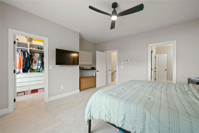 bedroom featuring light carpet, a walk in closet, a closet, and ceiling fan