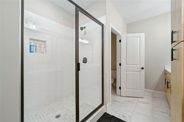 bathroom featuring vanity, a shower with door, and toilet