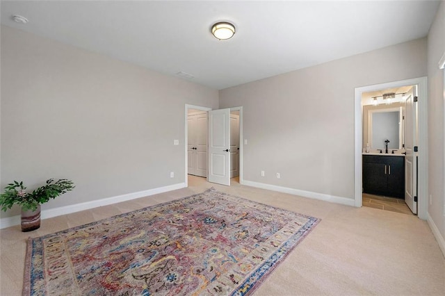 bedroom featuring ensuite bathroom and light carpet