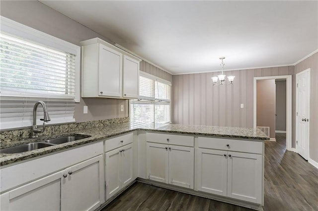 kitchen with dark wood-type flooring, sink, kitchen peninsula, white cabinetry, and decorative light fixtures