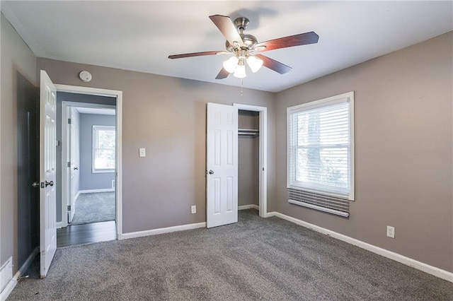 unfurnished bedroom with ceiling fan, dark colored carpet, and multiple windows