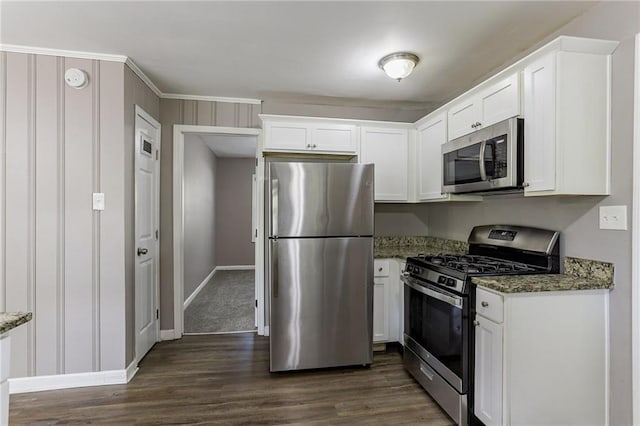 kitchen with appliances with stainless steel finishes, dark stone countertops, and white cabinetry