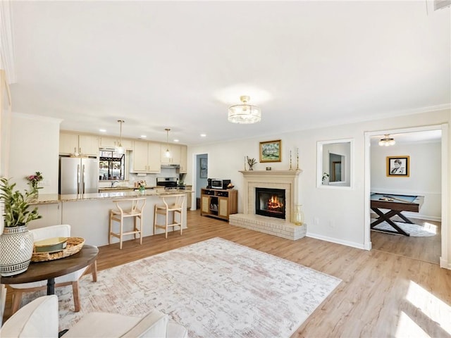 2466 Thrasher Rd, Buford, GA 30519 - living area featuring light wood-type flooring, recessed lighting, a brick fireplace, baseboards, and crown molding