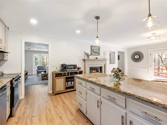 2466 Thrasher Rd, Buford, GA 30519 - kitchen with stainless steel appliances, ornamental molding, under cabinet range hood, a lit fireplace, and light wood-type flooring