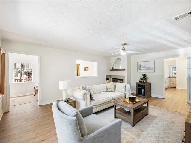 2466 Thrasher Rd, Buford, GA 30519 - living room featuring a ceiling fan, light wood-style floors, plenty of natural light, and a textured ceiling