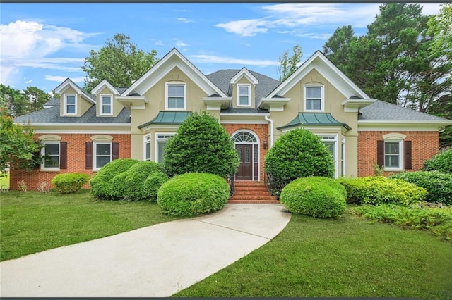 110 Glen Eagle Way, Mcdonough, GA 30253 - view of front of home featuring brick siding, a front yard, roof with shingles, stucco siding, and a standing seam roof