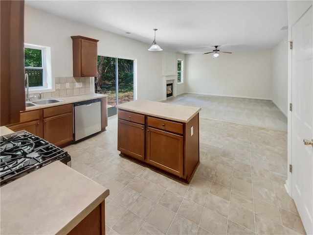 kitchen featuring dishwasher, hanging light fixtures, ceiling fan, a kitchen island, and sink