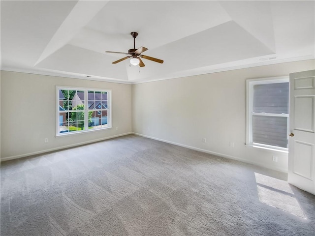 carpeted empty room with ceiling fan, a tray ceiling, and ornamental molding