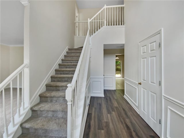 staircase featuring a towering ceiling and hardwood / wood-style flooring