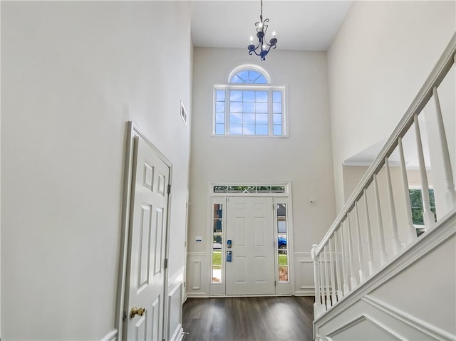 foyer entrance featuring dark wood-type flooring, a towering ceiling, and a chandelier