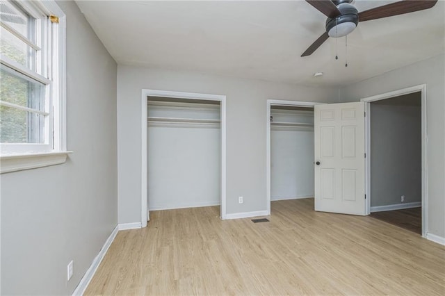 unfurnished bedroom with ceiling fan, multiple closets, and light hardwood / wood-style flooring