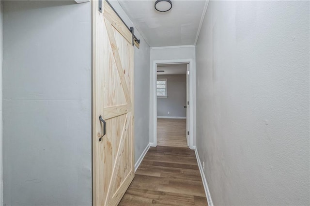 corridor with a barn door, crown molding, and hardwood / wood-style flooring