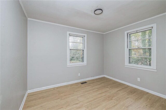 empty room with light hardwood / wood-style flooring, a healthy amount of sunlight, and crown molding