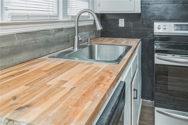 kitchen featuring white cabinetry, sink, stainless steel appliances, butcher block countertops, and decorative backsplash