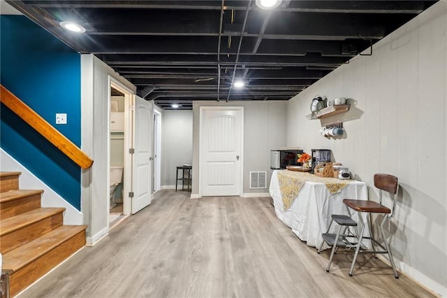 finished basement featuring stairway, wood finished floors, visible vents, and baseboards