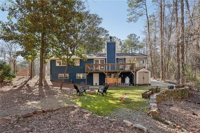 rear view of house with a storage unit, an outbuilding, a deck, an outdoor fire pit, and a chimney