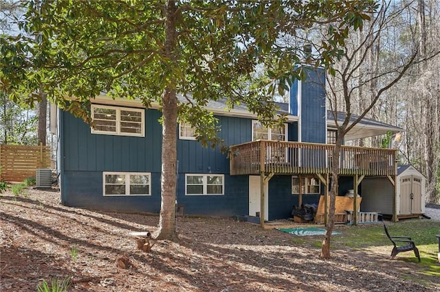 rear view of property with fence, a wooden deck, a chimney, a storage shed, and an outbuilding