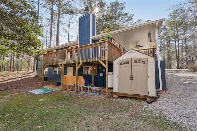 rear view of property featuring an outbuilding, a deck, a chimney, and a shed