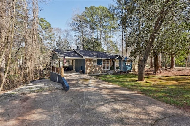 view of front facade with an attached carport, a front yard, and driveway