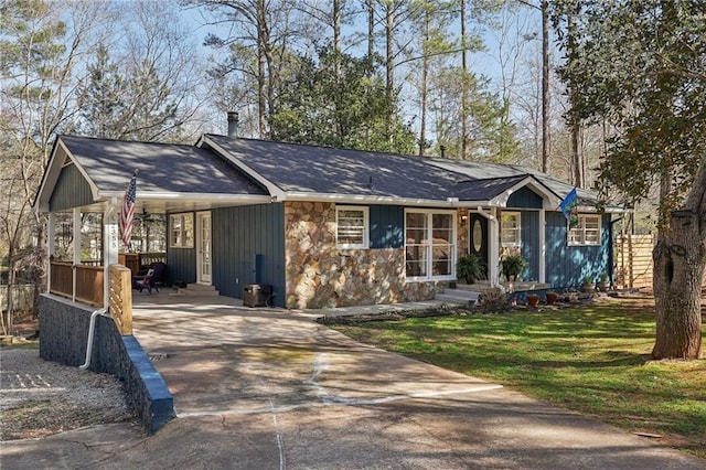 view of front facade featuring stone siding, concrete driveway, and a front lawn