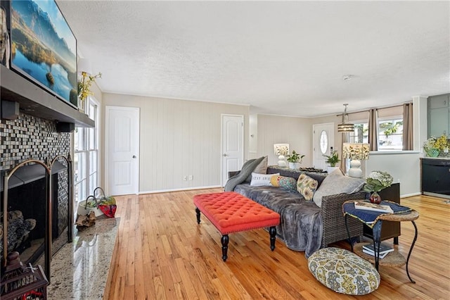 living room featuring baseboards, a textured ceiling, a brick fireplace, and hardwood / wood-style floors