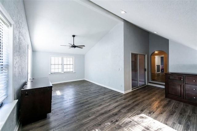 5479 Dorsett Shoals Rd, Douglasville, GA 30135 - unfurnished living room featuring ceiling fan, arched walkways, dark wood-type flooring, baseboards, and high vaulted ceiling
