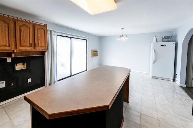 5479 Dorsett Shoals Rd, Douglasville, GA 30135 - kitchen with freestanding refrigerator, brown cabinets, a chandelier, arched walkways, and a kitchen island