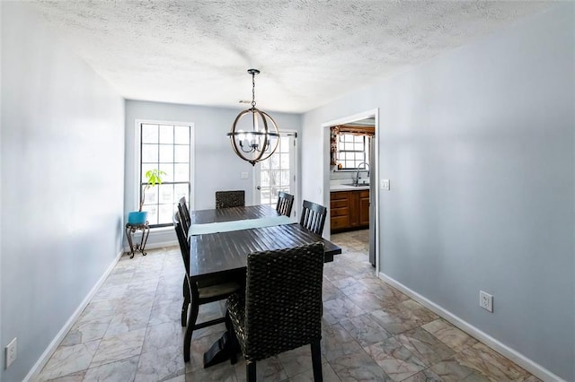 5479 Dorsett Shoals Rd, Douglasville, GA 30135 - dining area with a chandelier, baseboards, a textured ceiling, and light marble finish flooring