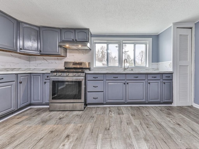 kitchen with sink, gray cabinetry, backsplash, gas range, and light wood-type flooring