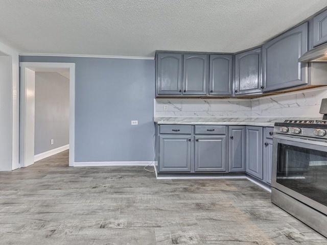 kitchen featuring backsplash, gray cabinets, light hardwood / wood-style floors, and stainless steel range with gas stovetop