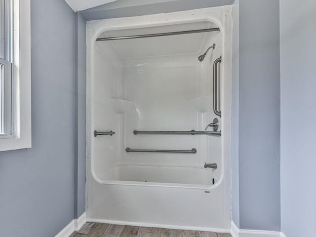 bathroom with hardwood / wood-style flooring and shower / washtub combination