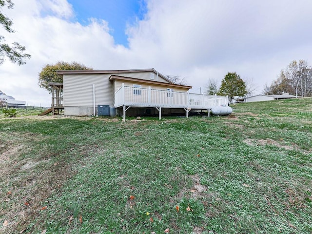 back of property featuring a wooden deck, central air condition unit, and a lawn