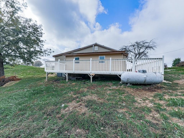 rear view of house featuring a wooden deck and a yard