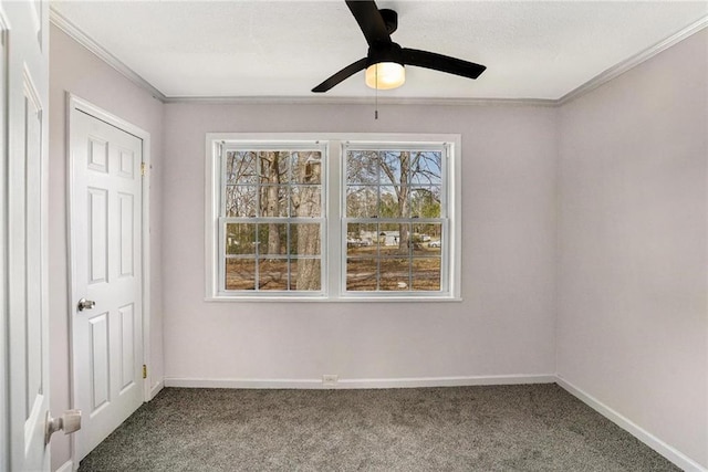 empty room featuring a ceiling fan, carpet flooring, crown molding, and baseboards