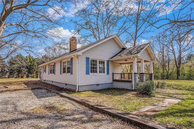 view of home's exterior with crawl space, covered porch, a lawn, and a chimney